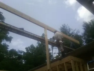 Carpenter setting a ridge beam over a new addition frame — Ice Dam Removal by Roofing Brothers in Appalachia
