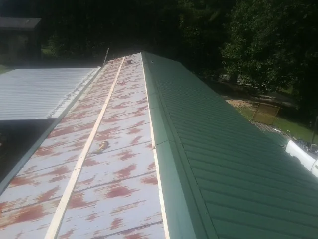 Old rusted panels beside newly installed green metal roofing — Wind Damage Roof Repair by Roofing Brothers in Appalachia