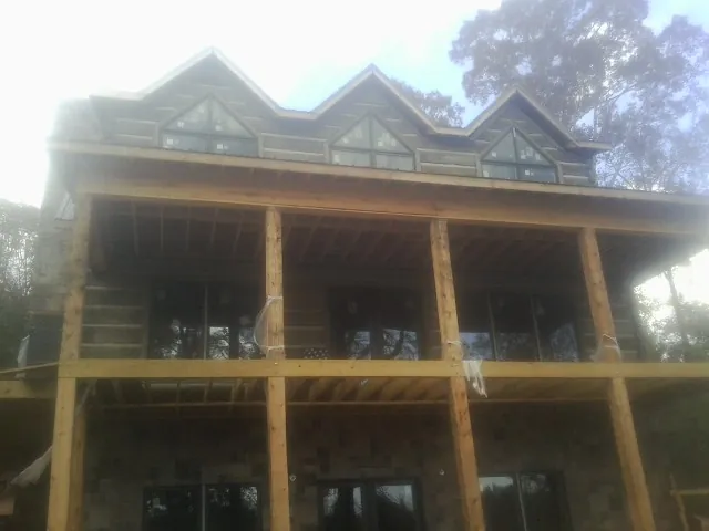 Dormers and porch framing on a large log home under construction — Roof Coating work by our crew in Appalachia