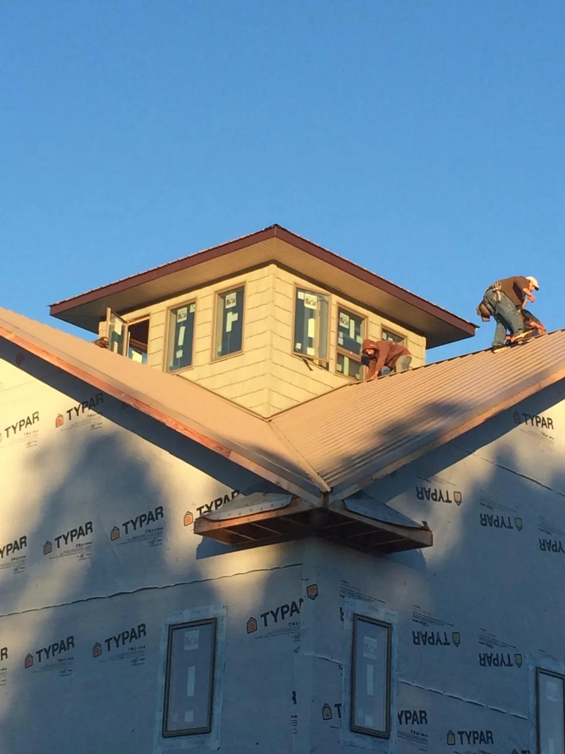 Roofers working around a rooftop cupola on a new metal roof at sunset — Roof Waterproofing in Appalachia by Roofing Brothers